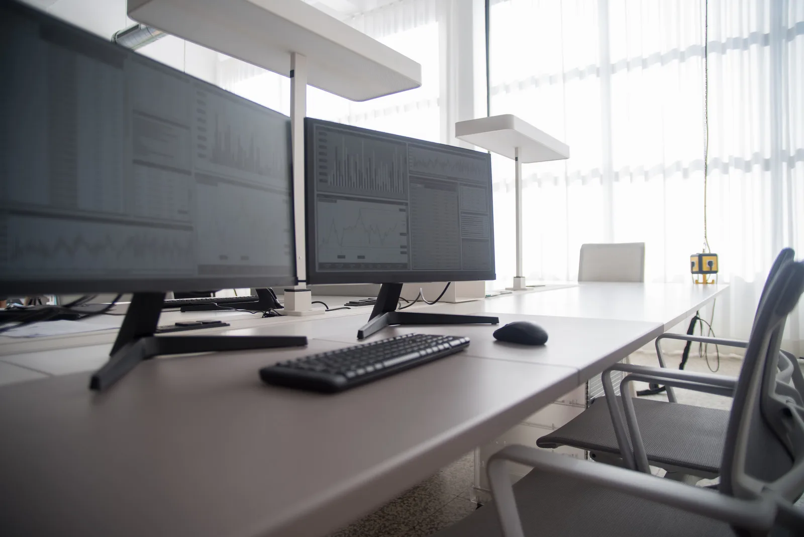 Stylish contemporary office featuring multiple computer monitors and ergonomic chairs.
